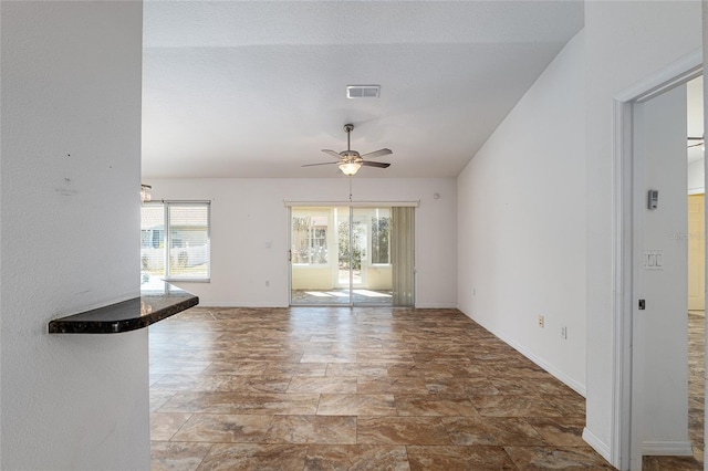 unfurnished room with visible vents, stone finish flooring, baseboards, lofted ceiling, and a ceiling fan