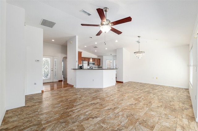 unfurnished living room with visible vents, arched walkways, ceiling fan with notable chandelier, and vaulted ceiling