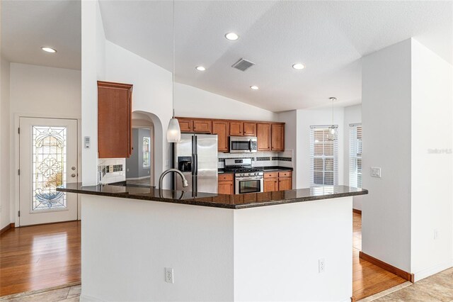 kitchen with visible vents, lofted ceiling, decorative backsplash, stainless steel appliances, and a sink