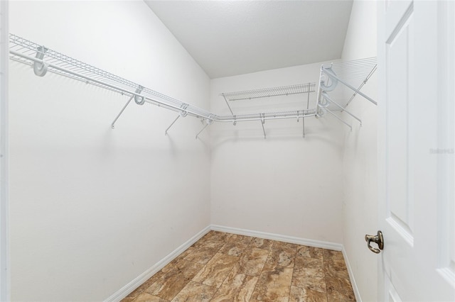 walk in closet featuring stone finish flooring