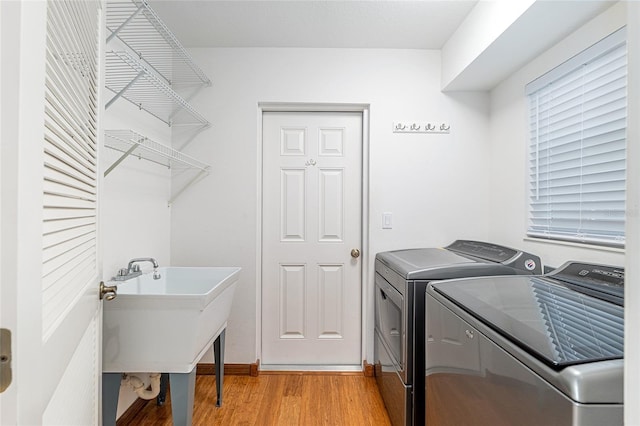 laundry room with a sink, laundry area, light wood-type flooring, and washing machine and clothes dryer