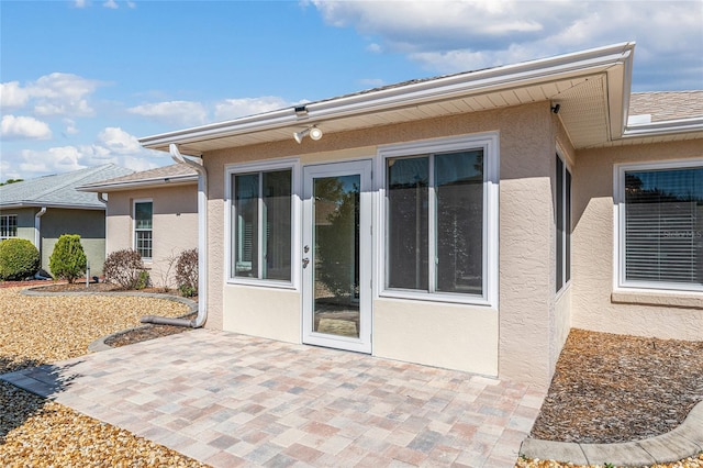 rear view of house with stucco siding and a patio