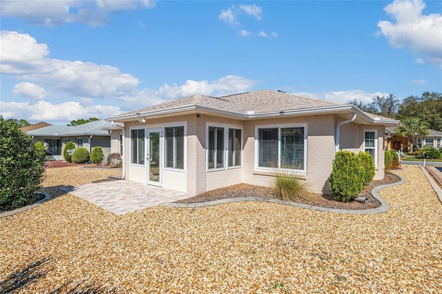 rear view of property with a shingled roof, a patio, french doors, and stucco siding