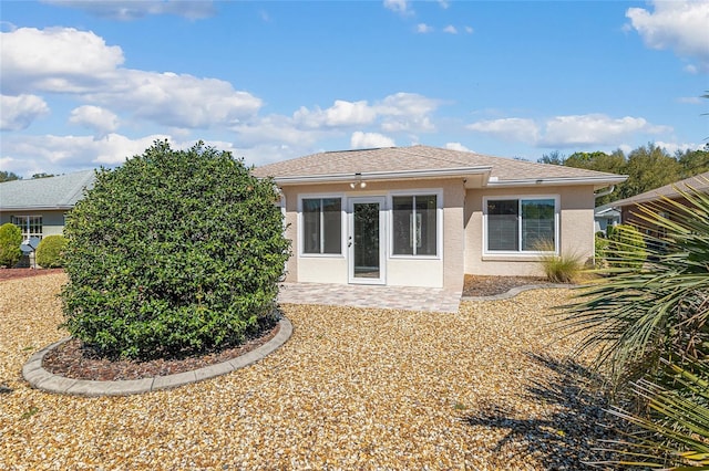 back of property with stucco siding, a patio, and roof with shingles