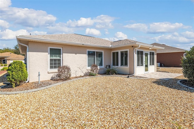 rear view of property with stucco siding and roof with shingles