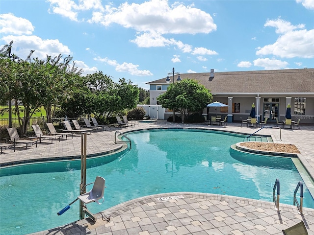 community pool with a patio and fence