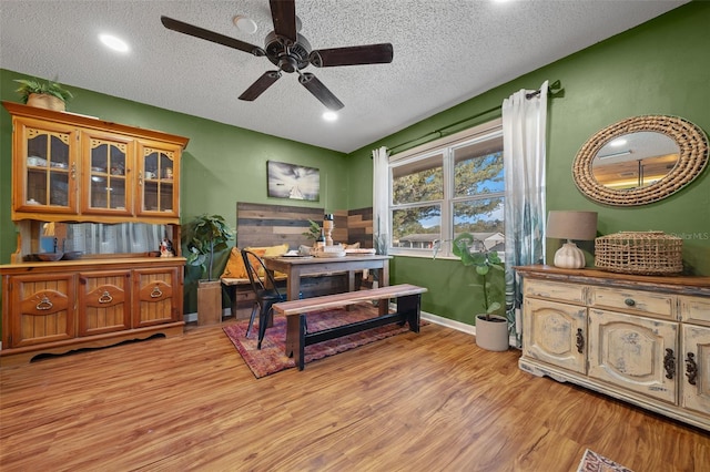 interior space featuring light wood-type flooring, a textured ceiling, and ceiling fan