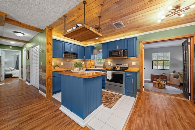 kitchen featuring visible vents, blue cabinetry, butcher block countertops, appliances with stainless steel finishes, and tasteful backsplash