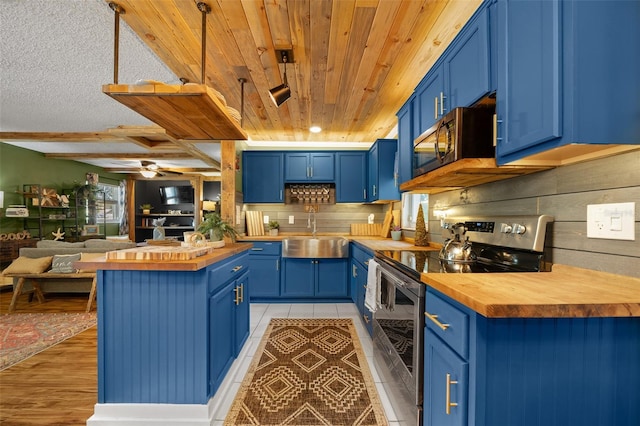 kitchen with blue cabinetry, stainless steel appliances, and wood counters