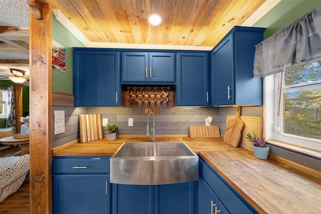 kitchen featuring blue cabinets, wood counters, a wealth of natural light, and a sink