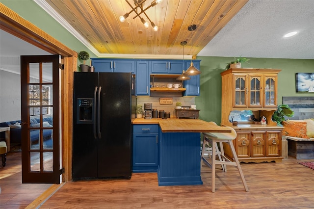 kitchen featuring blue cabinets, wooden ceiling, butcher block counters, and black refrigerator with ice dispenser