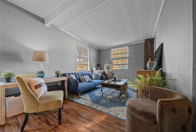 living room featuring lofted ceiling with beams, wood finished floors, ornamental molding, and a textured wall