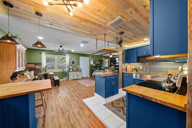 kitchen featuring blue cabinetry, butcher block countertops, and a sink