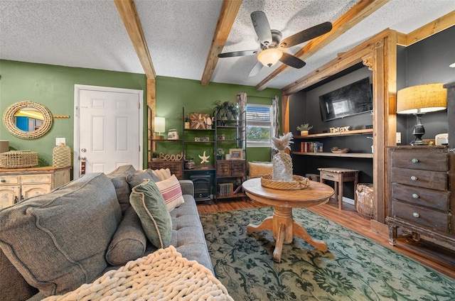 living area with beamed ceiling, a textured ceiling, and wood finished floors