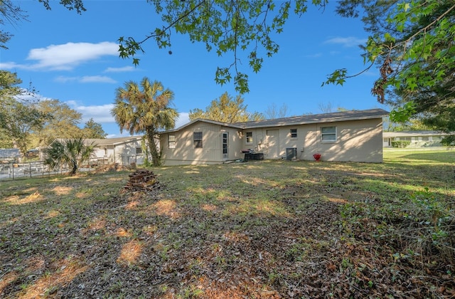 rear view of house with central air condition unit, a yard, and fence