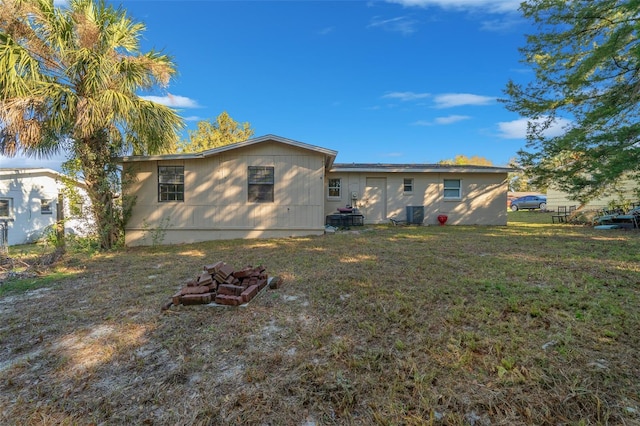 rear view of house with a yard, central air condition unit, and an outdoor fire pit