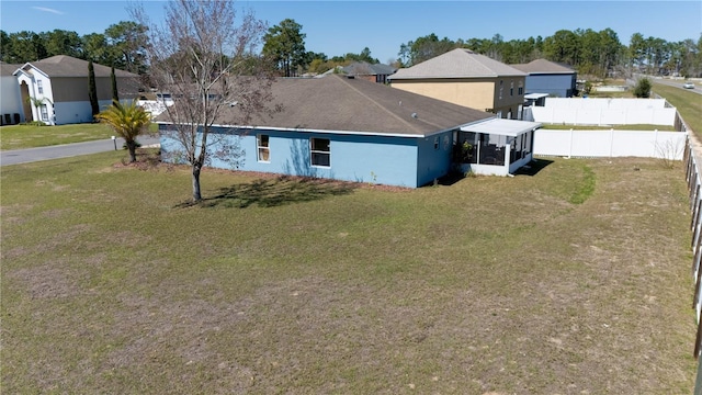 back of house with a residential view, stucco siding, a yard, and fence