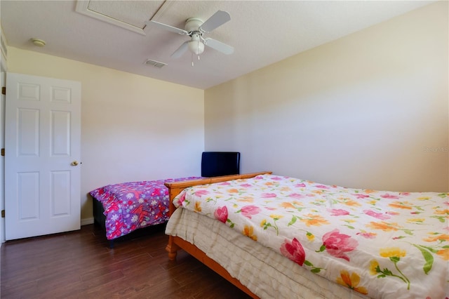 bedroom with dark wood finished floors, visible vents, attic access, and ceiling fan