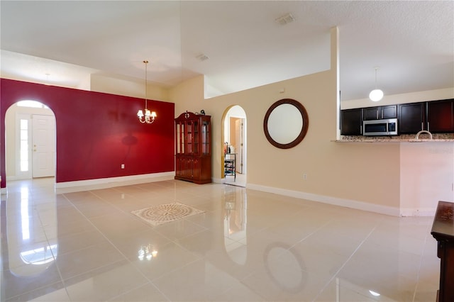 interior space featuring light tile patterned floors, baseboards, arched walkways, and visible vents