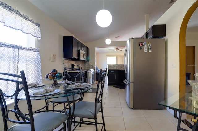 dining area featuring light tile patterned floors, arched walkways, ceiling fan, and vaulted ceiling