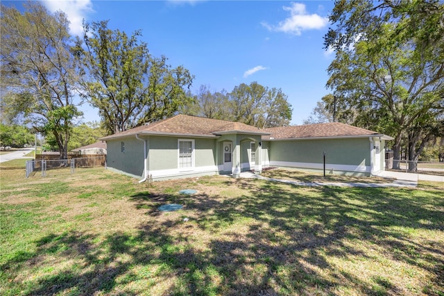 view of front of home with stucco siding, a front yard, and fence