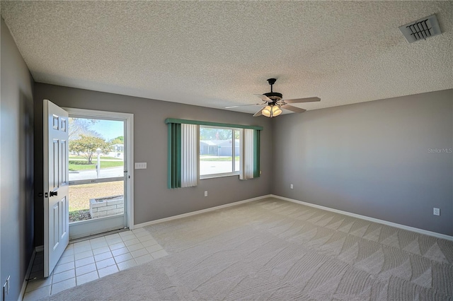 interior space featuring visible vents, baseboards, light carpet, a textured ceiling, and a ceiling fan
