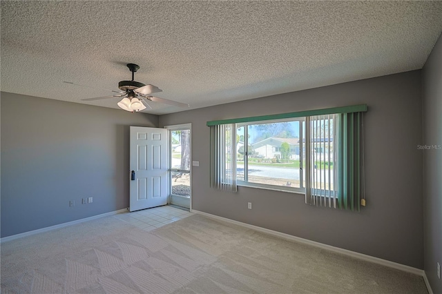 unfurnished room featuring a textured ceiling, carpet, baseboards, and ceiling fan