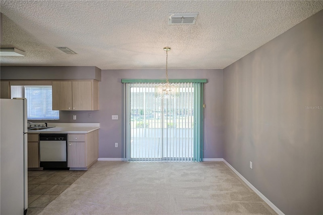 kitchen featuring visible vents, an inviting chandelier, freestanding refrigerator, light countertops, and dishwasher