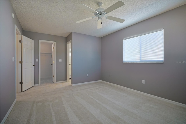 empty room with baseboards, light colored carpet, a textured ceiling, and ceiling fan