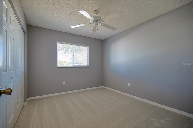 unfurnished room with light carpet, a textured ceiling, baseboards, and ceiling fan