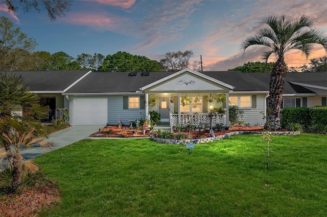 view of front of property with a yard, an attached garage, covered porch, and driveway