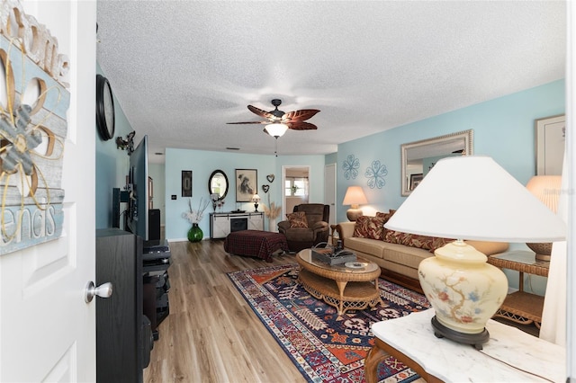 living area featuring a textured ceiling, ceiling fan, and wood finished floors