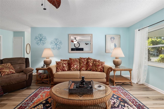 living area featuring a textured ceiling, ceiling fan, and wood finished floors