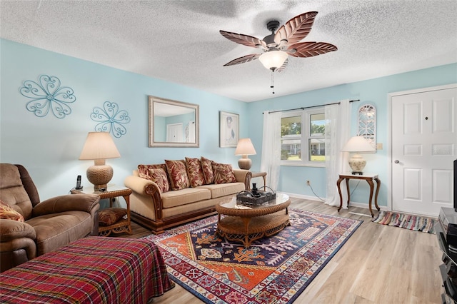 living area with a textured ceiling, wood finished floors, baseboards, and ceiling fan