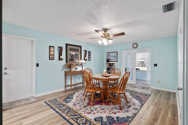 dining area featuring visible vents, ceiling fan, baseboards, and wood finished floors