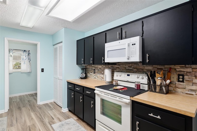 kitchen with light wood-style flooring, a textured ceiling, dark cabinetry, white appliances, and baseboards