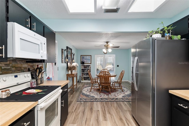 kitchen featuring visible vents, wooden counters, white appliances, a textured ceiling, and dark cabinets