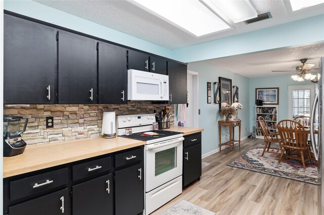 kitchen featuring visible vents, light wood finished floors, white appliances, light countertops, and dark cabinets