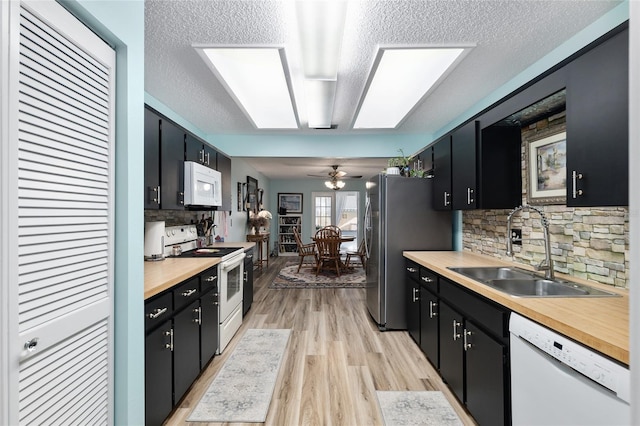 kitchen with white appliances, dark cabinets, and a sink