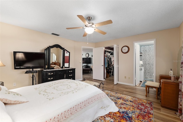 bedroom with visible vents, light wood-style flooring, a textured ceiling, and ensuite bathroom