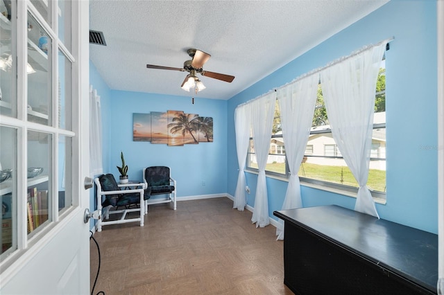 office area with visible vents, baseboards, a textured ceiling, and a ceiling fan