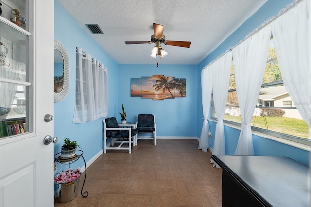 office area with visible vents, ceiling fan, a textured ceiling, and baseboards