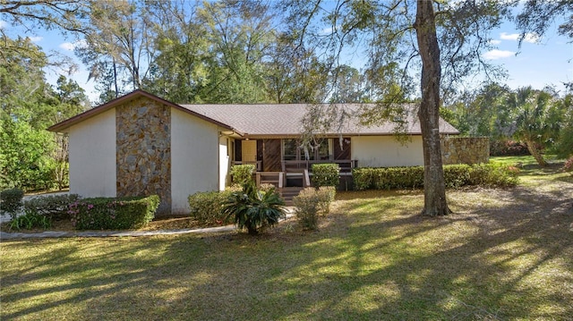 exterior space featuring a front lawn, stone siding, and stucco siding