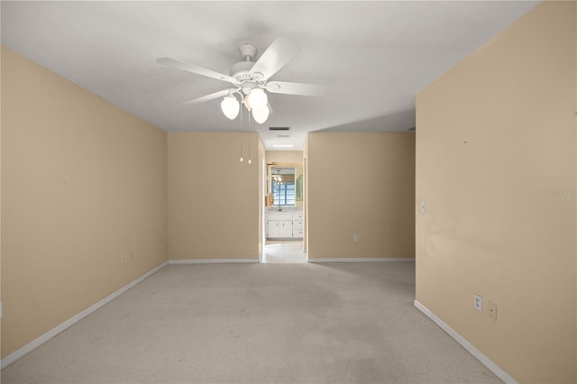 spare room featuring light carpet, visible vents, baseboards, and a ceiling fan