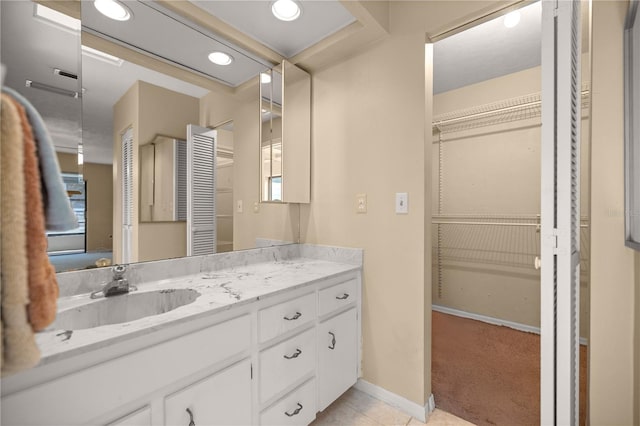 bathroom with tile patterned floors, a closet, baseboards, and vanity