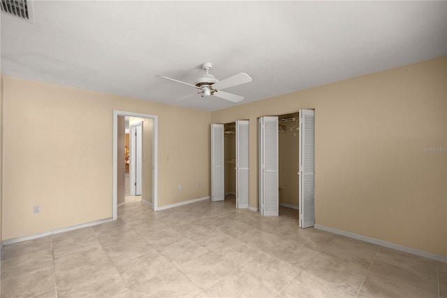 unfurnished bedroom featuring visible vents, multiple closets, baseboards, and a ceiling fan