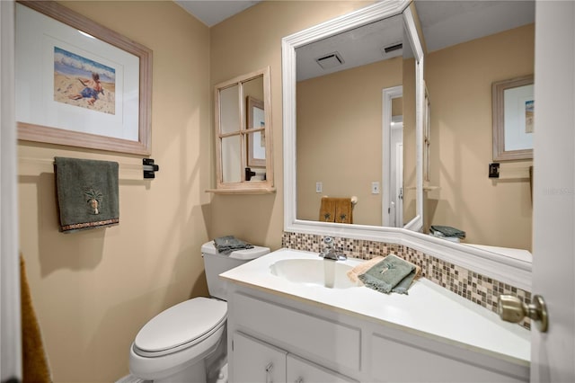 bathroom with decorative backsplash, toilet, vanity, and visible vents