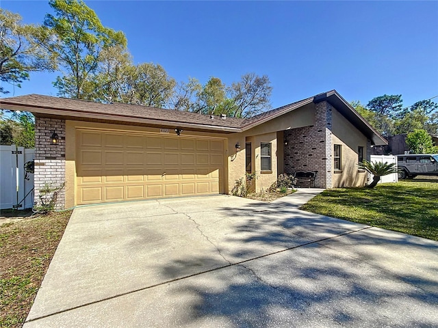 view of front of home with a front yard, driveway, an attached garage, stucco siding, and brick siding