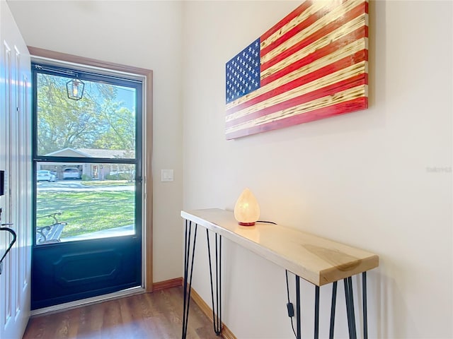 doorway to outside featuring baseboards and wood finished floors