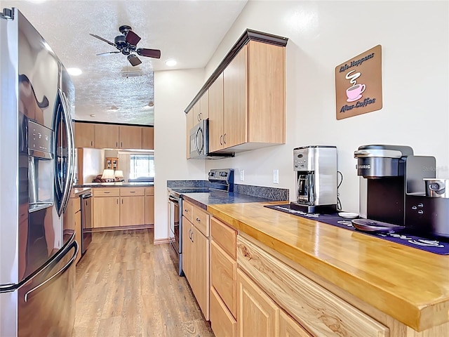 kitchen with light brown cabinets, ceiling fan, light wood-style floors, a textured ceiling, and stainless steel appliances